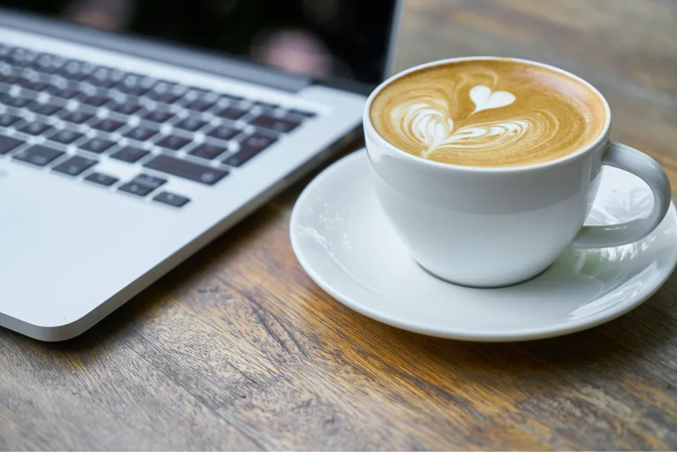 Freshly brewed coffee next to a computer