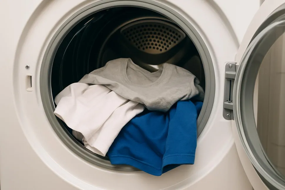 Dryer door open with cotton T-shirts inside