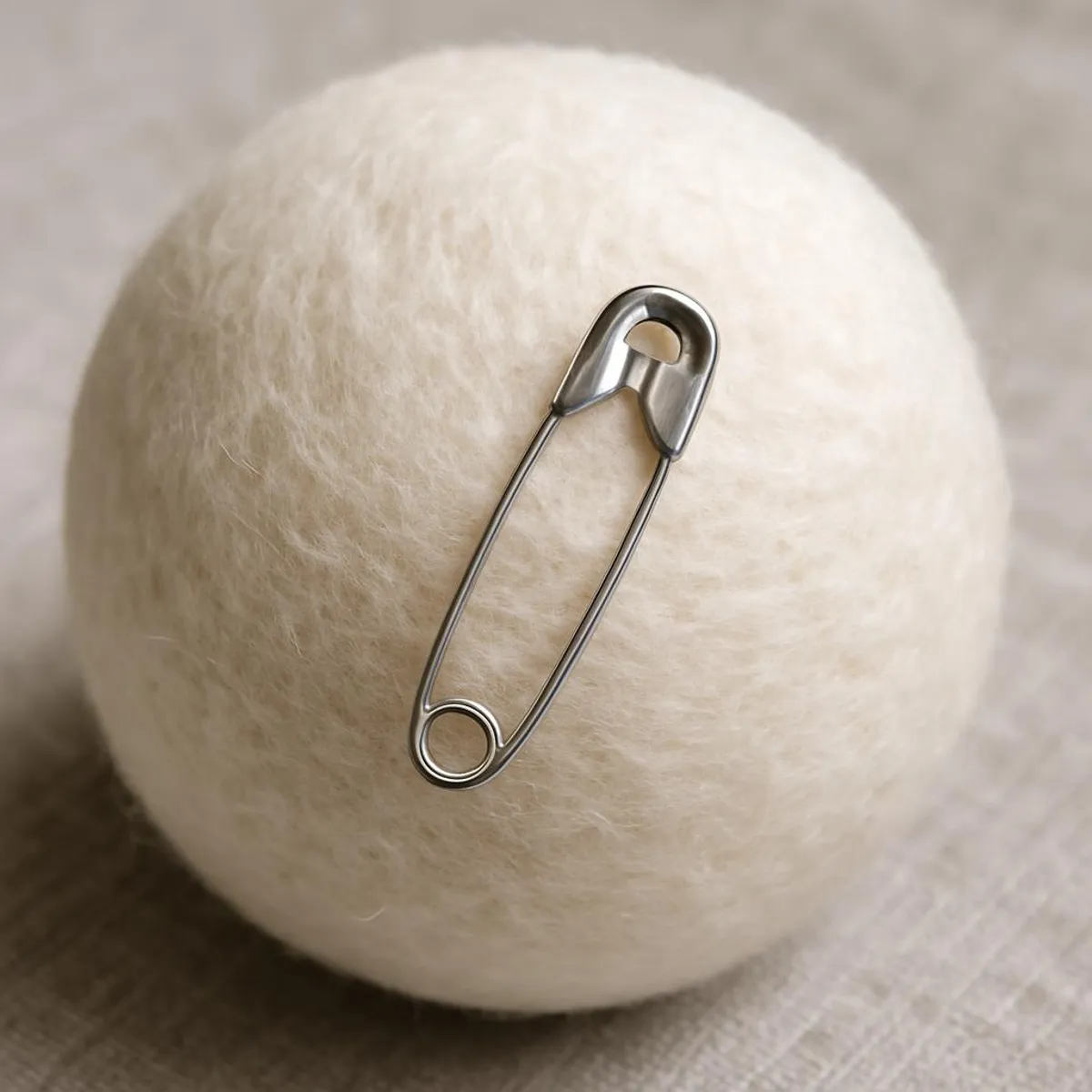Metal safety pin clipped to wool dryer ball as a static hack