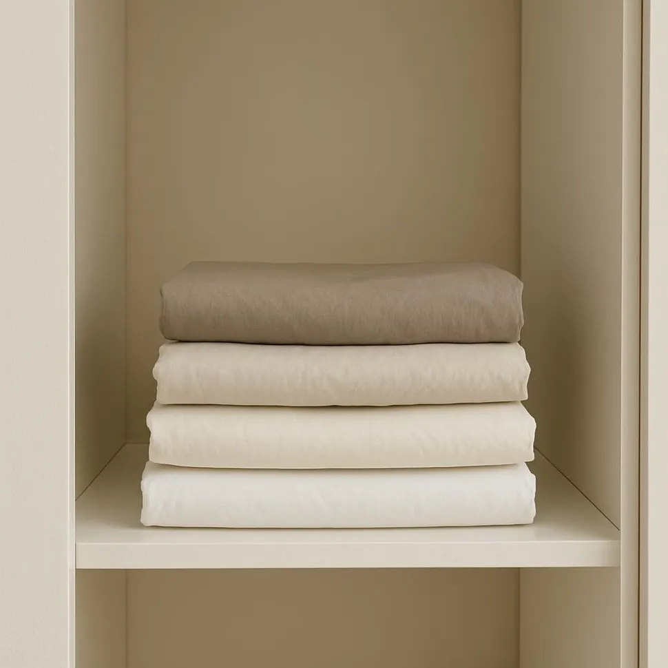 Neatly folded bed sheets stacked in a minimalist closet